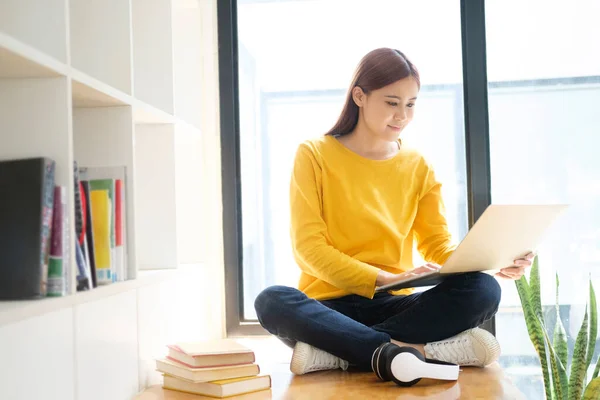 年轻妇女在网上工作或学习 同时坐在自家空间的地板上 使用笔记本电脑做研究或做家务 在线工作和学习概念 — 图库照片