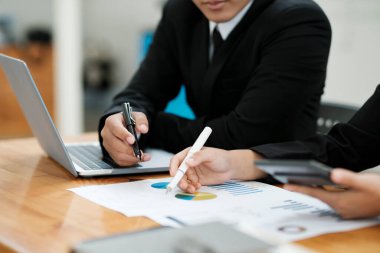 İş adamları ya da iş arkadaşları iş yerlerinde dizüstü bilgisayar ve grafikler kullanarak proje üzerinde birlikte çalışır, tartışır, fikir paylaşır, plan yapar ve iş stratejisi ve finansmanı analiz ederler..