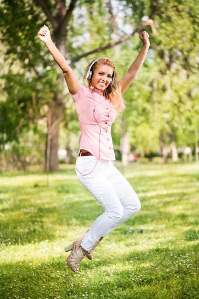 Joyeux jeune femme sautant dans le parc — Photo