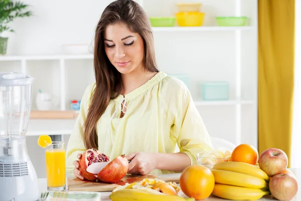 Giovane donna affettare melograno — Foto Stock