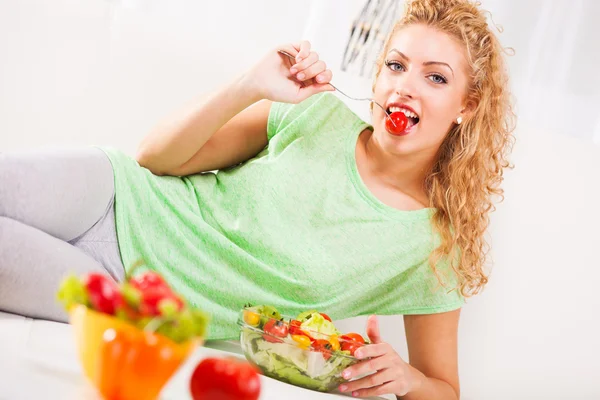 Ung kvinna äta tomat — Stockfoto