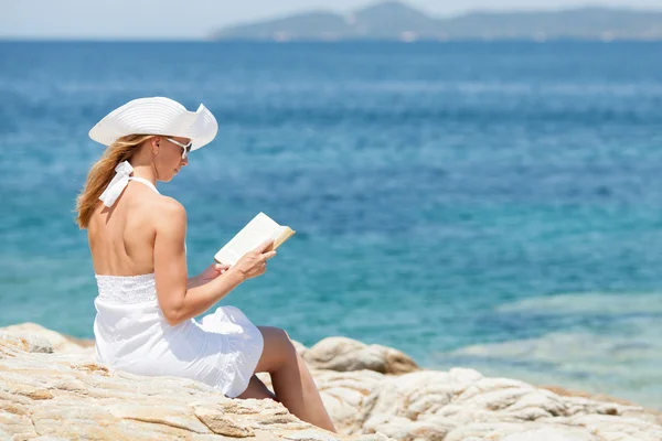 Mujer joven leyendo libro en la playa — Foto de Stock