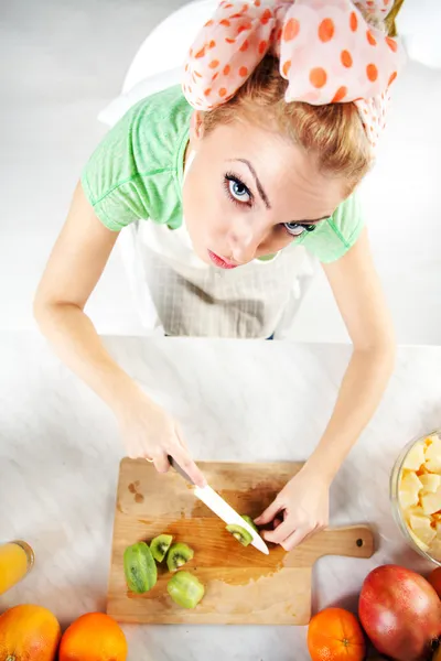 Jovem mulher cortando kiwi — Fotografia de Stock