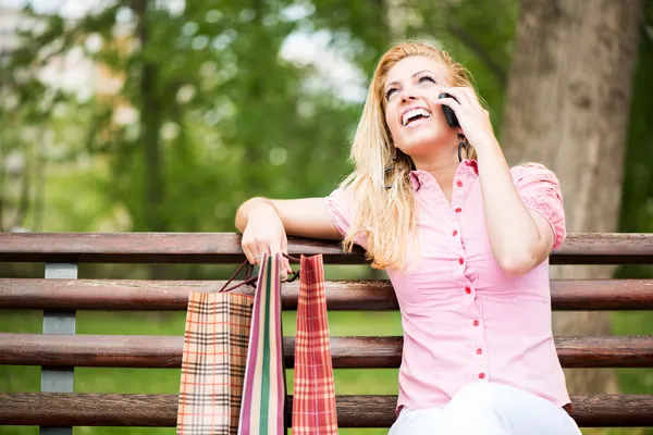 Gelukkig meisje met shopping tassen na een telefoongesprek — Stockfoto