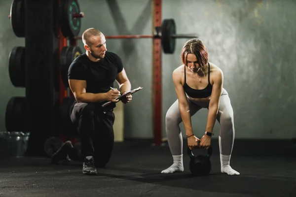 Мускулистая Молодая Женщина Тренируется Тренером Спортзале Накачивает Мускулы Гирями — стоковое фото