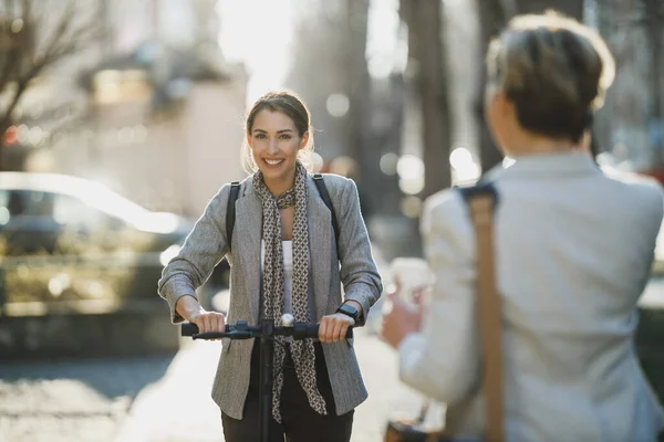 仕事の途中で電動スクーターに乗っている若いビジネス女性 — ストック写真