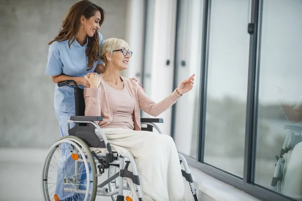 开枪射击一名照顾一名坐轮椅的老年女性病人的年轻女护士 — 图库照片