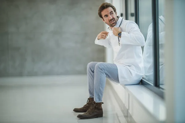 Aufnahme Eines Müden Reifen Arztes Der Neben Einem Fenster Sitzt — Stockfoto