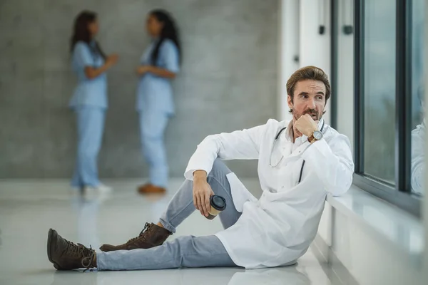 Médico Cansado Sentado Suelo Pensativo Mirando Por Ventana Mientras Toma —  Fotos de Stock