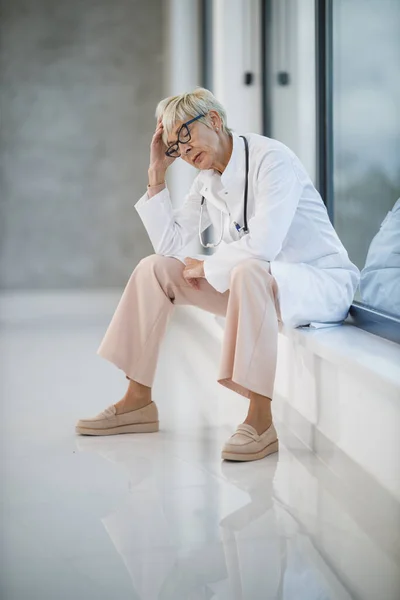 Tiro Médico Sênior Olhando Estressado Enquanto Sentado Chão Perto Uma — Fotografia de Stock