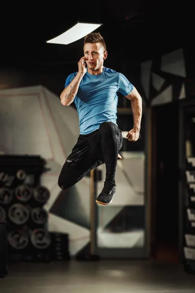 ジムで働いている間に空中を飛び回るスポーツウェアのハンサムな筋肉の男のショット — ストック写真