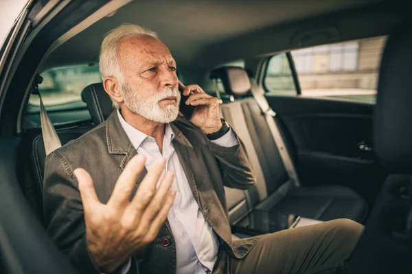 노인이 출퇴근중 자동차 뒷자리에 스마트폰으로 통화하는 모습을 — 스톡 사진