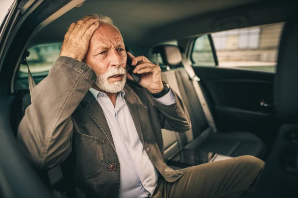 彼の朝の通勤中に車の後部座席に座っている間にスマートフォンで話して成功した先輩ビジネスマンのショット — ストック写真