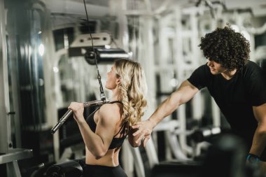 Genç kaslı bir kadın spor salonunda antrenman yapıyor..