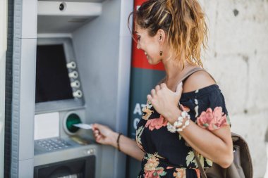 Kredi kartı ekleyen ve ATM 'den para çeken bir kadının yan görüntüsü.