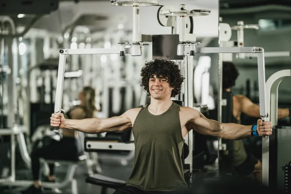Joven Musculoso Está Entrenando Máquina Gimnasio —  Fotos de Stock