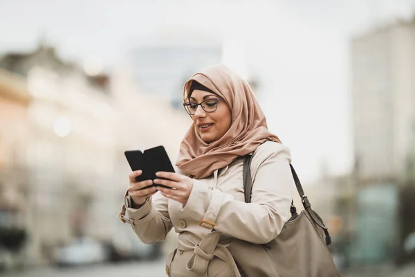 Lachende Moslimvrouw Draagt Een Hijab Tipt Berichten Haar Smartphone Terwijl — Stockfoto