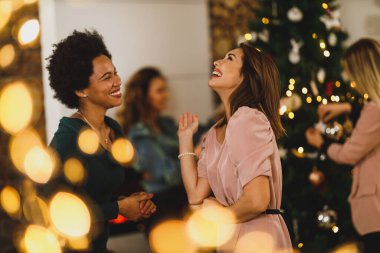 Neşeli çoklu etnik kadın arkadaşlar, yeni yıl partisinde, neşeli bir ortamda birlikte iyi vakit geçiriyorlar..