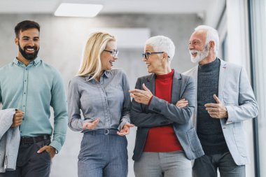 Bir grup güler yüzlü iş adamı modern ofiste yürüyor ve toplantı sırasında birbirleriyle tartışıyorlar..