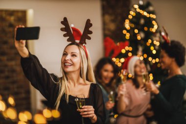 Neşeli bir kadın Noel 'de ya da yeni yıl partisinde kız arkadaşlarıyla selfie çekiyor..