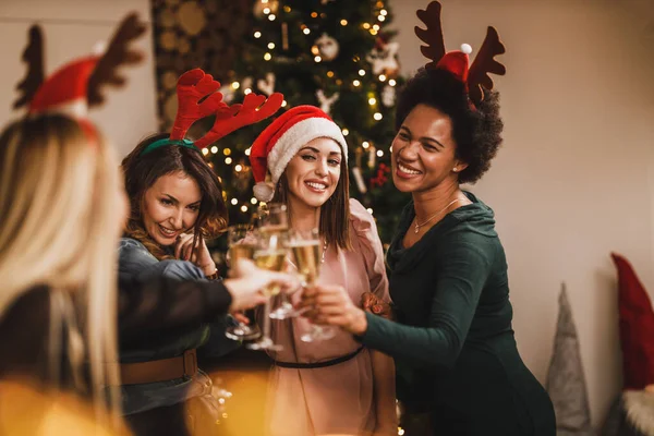 4人の陽気な多民族の女の子は クリスマスや新年のパーティーでシャンパンを楽しみながら楽しんでいます — ストック写真