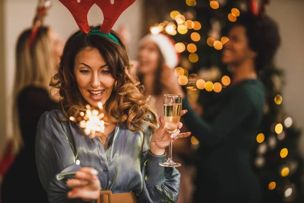シャンパンで乾杯し 彼女は自宅のパーティーで彼女の友人とクリスマスや新年を祝うように輝きと遊ぶ陽気な若い女性 — ストック写真
