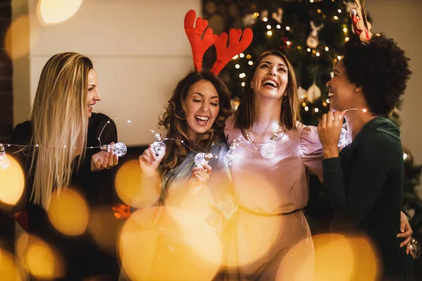 クリスマスや新年のホームパーティー中に電球で楽しんでいる4人の陽気な多民族の女の子 — ストック写真