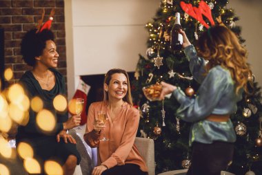 Neşeli çok ırklı bayan arkadaşlar Noel 'de ya da yeni yıl partisinde şampanya içerken eğleniyorlar..