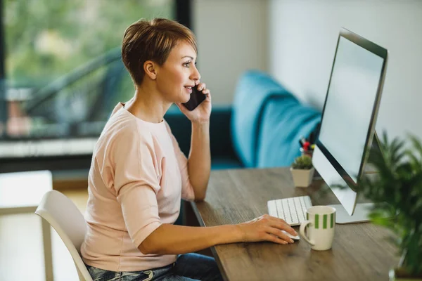 Frau Mittleren Alters Spricht Smartphone Während Sie Hause Computer Arbeitet — Stockfoto