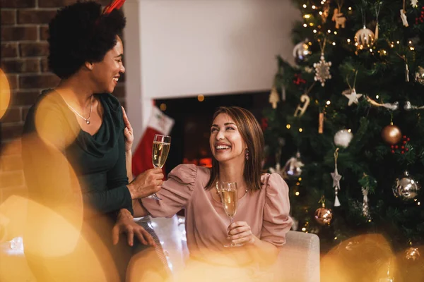 一緒に家で新年やクリスマスを祝いながら 楽しい時間を過ごし シャンパンで乾杯する陽気な多民族女性の友人 — ストック写真