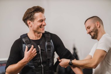 Kişisel antrenör orta yaşlı bir adama sağlık ekibi için giyinmesinde yardım ediyor..