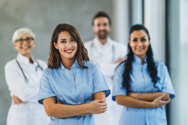 Hastane koridorunda kollarını kavuşturup kameraya bakan kendine güvenen doktor ve hemşirelerin portresi..