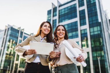 İki çekici, gülümseyen iş kadını iş görüşmesi yapıyor ve ofis dışında birlikte çalışmaktan zevk alıyor..
