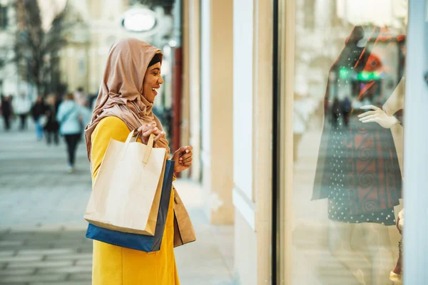快乐的黑人穆斯林女人 头戴头巾 提着购物袋走在街上 — 图库照片