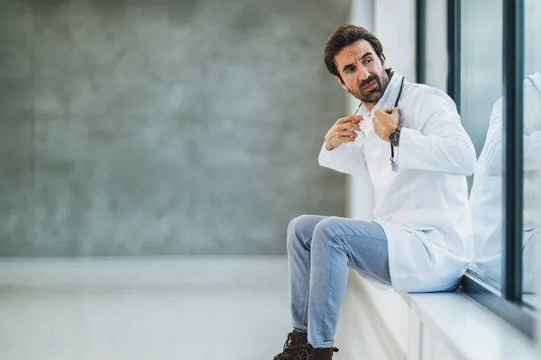 Müder Arzt Sitzt Leerem Krankenhausflur Und Blickt Besorgt Aus Dem — Stockfoto
