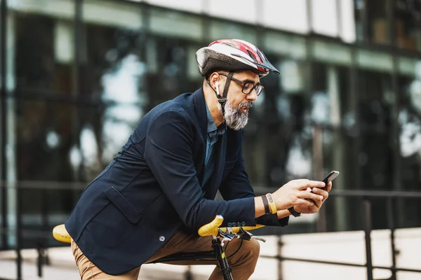 市内を自転車で移動する途中でスマートフォンを使用して成功した中高年実業家 — ストック写真