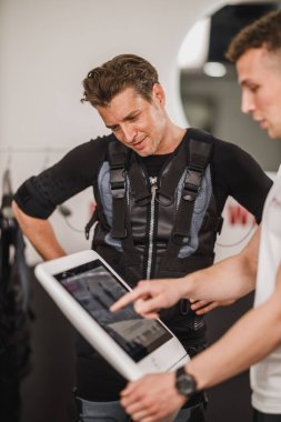 Orta yaşlı bir adam spor salonunda kişisel antrenörle acil yardım eğitimi alıyor..