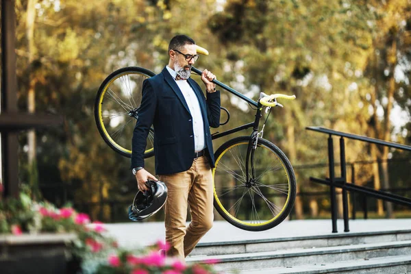 中年のビジネスマンが自転車で仕事に行き 階段の上で彼の肩に自転車を運ぶ — ストック写真