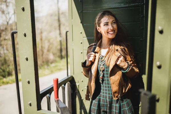 一个笑容满面的年轻女子站在一辆复古火车车厢里去冒险 — 图库照片