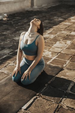 Rahat genç bir kadın terasta yoga yapıyor..