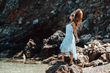 Mavi elbiseli güzel bir kadın güneşli bir günde kumsalda dinleniyor..