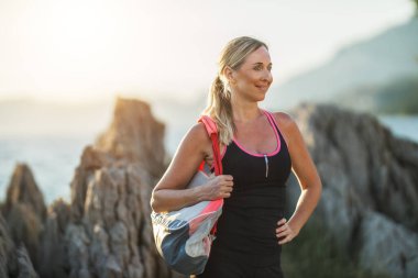 Formda orta yaşlı bir kadın sahile yakın bir yerde eğitime hazırlanıyor..