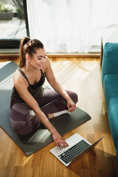 Young Woman Using Laptop While Doing Stretching Exercises Home Morning — стоковое фото