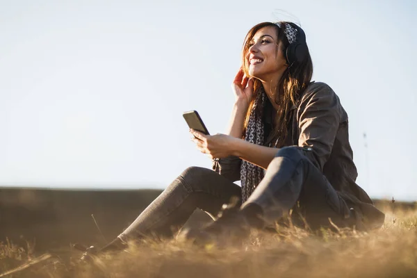 Schattige Pensive Vrouw Luisteren Muziek Van Haar Smartphone Terwijl Zitten — Stockfoto