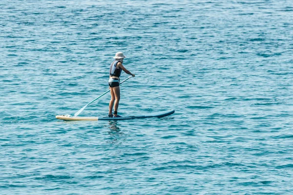 Happy boy paddling on SUP or stand up paddle board and having fun in ocean sea on a summer holiday.
