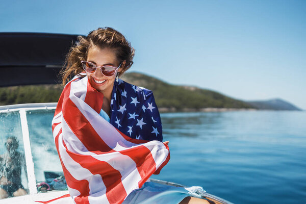 Attractive young woman with US national flag enjoying a relaxing day on a her private yacht.
