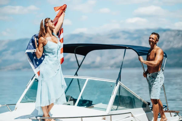 A loving couple with US national flag having fun and spending the day on her private yacht.