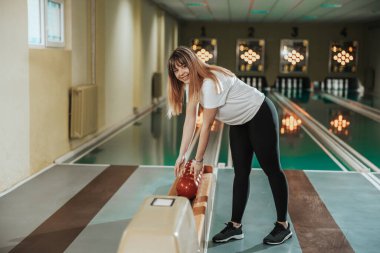 Shot of a cute young woman holding bowling ball in the bowling club.