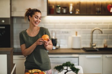 Shot of a happy young woman preparing a breakfast of fruit in her kitchen at home.