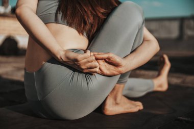 Close-up of a relaxed woman practicing yoga stretching exercise outdoors.